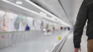 People walking on the moving walkway in the airport - blurred footage. Mid shot