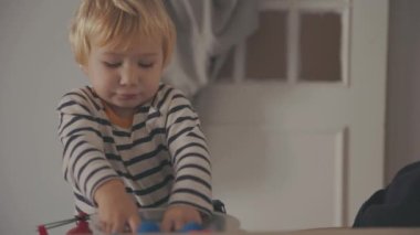 Cute little blonde boy playing with toys indoors. Mid shot