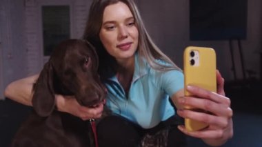 Cute smiling woman taking selfie with her dog. Mid shot