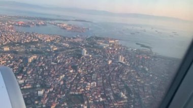 Uçak liman kenti üzerinden iniyor. Pencereden uçağın görüntüsü. Hava görünümü