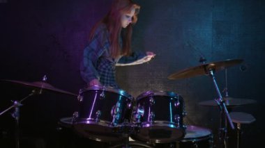 Şirin genç bayan davulcu oturur ve davul çalmaya başlar. Orta çekim