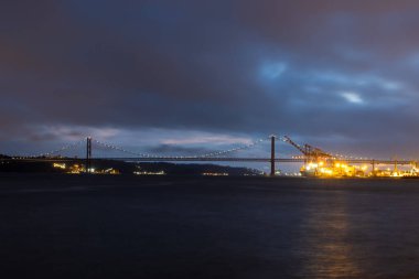 Tagus nehri ve 25 Nisan köprüsü - gece manzarası. Orta çekim