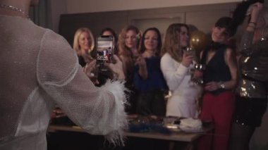 Partide eğlenen bir grup kadın telefon kamerasıyla fotoğraf çekiyor. Orta çekim