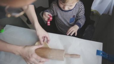Aile yemeği. Küçük bir çocuk çiğ hamura kurabiye bıçağı dayıyor. Orta çekim
