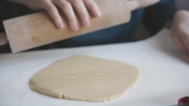 Aile yemekleri. Bir kadın çiğ hamuru oklavayla yuvarlar. Orta çekim