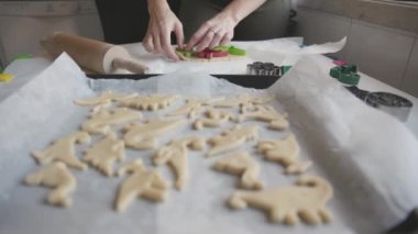 Kurabiye pişiren bir kadın dinozor hamurunu kalıpla keser. Orta çekim