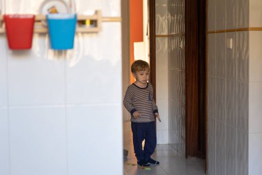 Apartmanın koridorunda küçük bir çocuk duruyor. Orta çekim