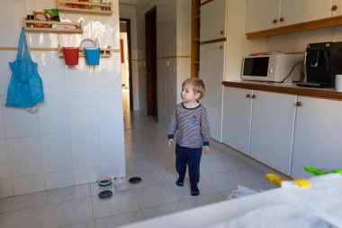 Küçük sarışın çocuk mutfağın ortasında duruyor. Orta çekim