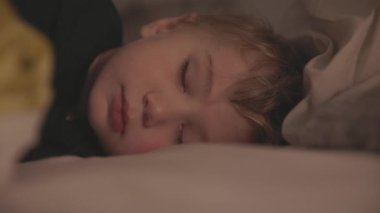 Küçük tatlı sarışın çocuk yatakta uyuyor. Orta çekim