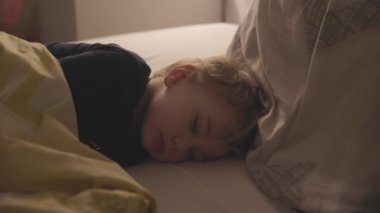 Küçük tatlı sarışın çocuk yatakta uyuyor. Orta çekim