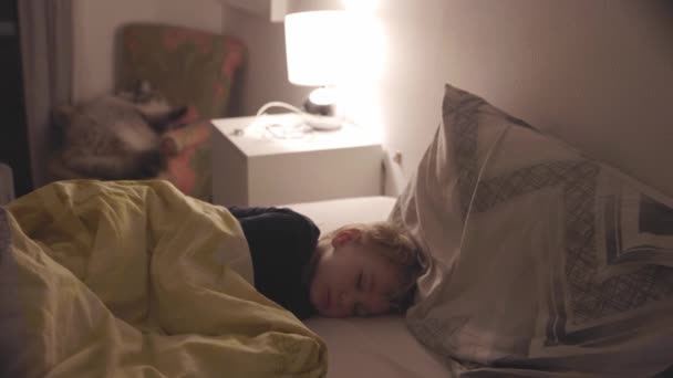 Blonde Little Boy Sleeps Big Bed Light Lamp Mid Shot — Stock Video