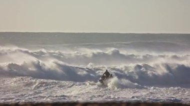 28 Şubat 2023 Nazare, Portekiz: iki kişi bir sörf ve jet ski ile deniz dalgalarına biniyor. Orta çekim