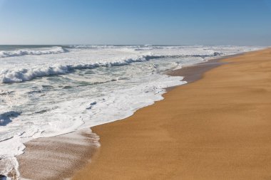 Deniz dalgaları kumlu sahili kaplıyor. Orta çekim