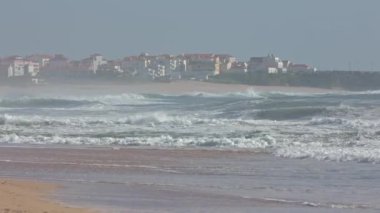 Nazare şehrindeki deniz dalgaları. Arkasında turuncu çatılar olan evler. Orta çekim