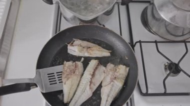 Kızart ve beyaz balığı spatulayla kızartma tavasında çevir. Orta çekim