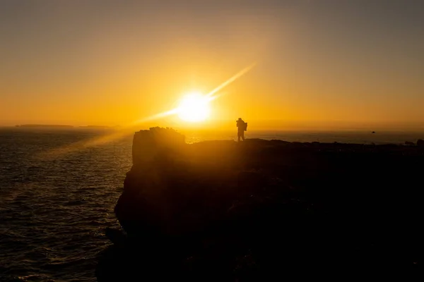 Silhouette Man Standing Top Cliff Taking Photos Sea Sunset Mid — Stock Photo, Image