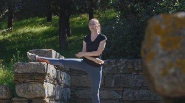 Atletik kadın parkta esneme hareketleri yapıyor. Orta çekim