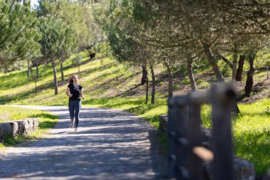 Fitness konsepti. Parkta koşan gözlüklü yetişkin bir kadın. Orta çekim