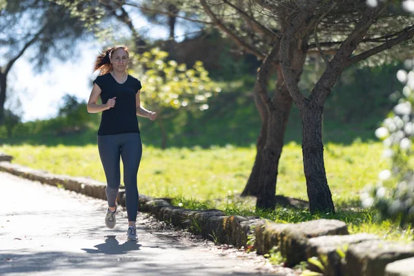 stock image An adult woman running in the green park. Mid shot