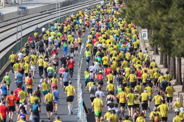 12 Mart 2023 Lizbon, Portekiz: Sarı tişörtlü insanlar köprüde maraton koşuyor. Orta çekim