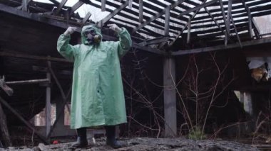 Koruyucu takım elbiseli ve gaz maskeli orta parmaklı bir adam. Orta çekim