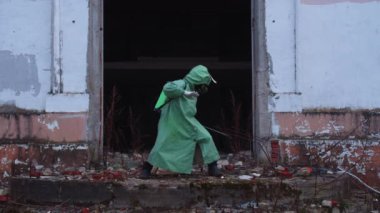 Gaz maskeli ve koruyucu kıyafetli bir adam kıyamet sonrası dünyasında dans ederken deliriyor. Orta çekim