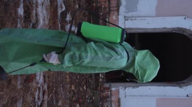 Kıyamet sonrası konsepti. Gaz maskeli ve koruyucu giysili bir adam terk edilmiş binada yürüyor ve kameraya bakmak için geri dönüyor. Dikey çekim