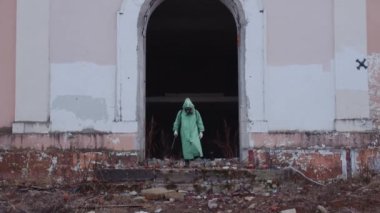 Gaz maskeli ve koruyucu giysili bir adam dağınık alanda yürüyor. Orta çekim