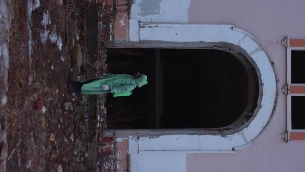 ガソリンマスクの男と周りを見回す保護スーツと放棄された建物の中を歩く — ストック動画