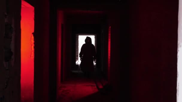 一个穿着防护服 戴着防毒面具的男人走在红色灯光下的废弃大楼里 — 图库视频影像