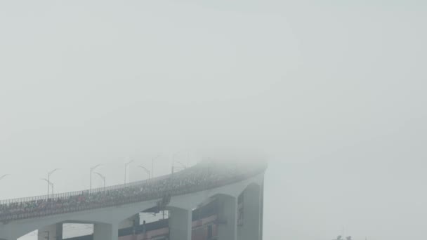 濃い白い霧の中 橋の上でマラソンを走る人々の群衆 ミッドショット — ストック動画
