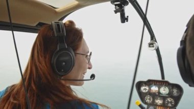 Bir kadın bir helikopterin yolcu koltuğunda oturuyor. Orta çekim