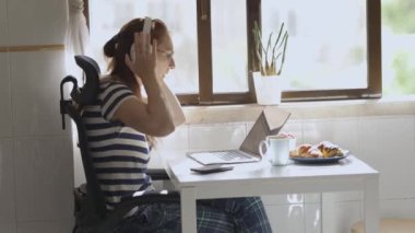 Kulaklıklı yetişkin bir iş kadını bilgisayarı kullanarak masada çalışıyor. Orta çekim