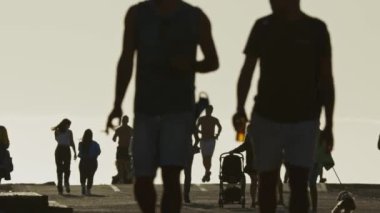 19 Nisan 2023 Lizbon, Portekiz: Costa da Caparica - deniz kenarında yürüyen turist siluetleri. Orta çekim