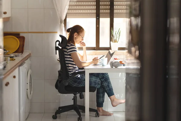 stock image Thoughtful woman freelancer working at her phone at the kitchen table. Mid shot