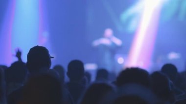 İnsanlar mavi ışıkta canlı bir rap konserinden hoşlanırlar. Orta çekim