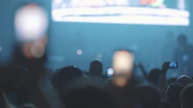 Kalabalıktaki insanlar telefonlarıyla bir rap konserinin canlı performansını kaydediyorlar. Orta çekim