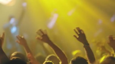 İnsanlar canlı konserlerde kollarını yana doğru sallıyorlar. Orta çekim