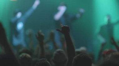 Kalabalıktaki insanlar konserde el sıkışıyorlar. Orta çekim