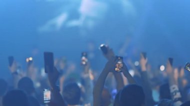 Konserdeki insanlar gösteriyi sahnede telefonlarıyla çekiyorlar. Orta çekim