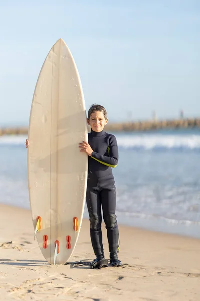 Маленький Улыбающийся Мальчик Стоящий Берегу Моря Большой Доской Серфинга Вертикальный — стоковое фото