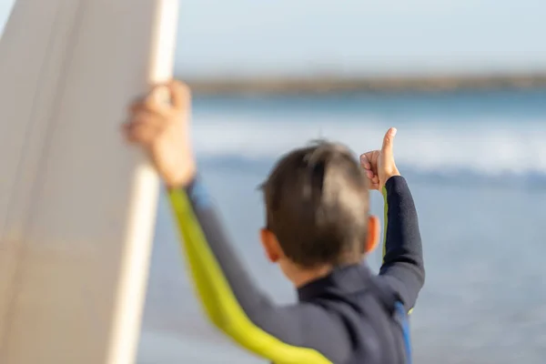 Маленький Хлопчик Гідрокостюмі Показує Великі Пальці Вгору Дивлячись Дошку Серфінгу — стокове фото