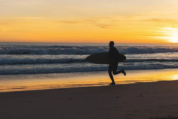 Ein Mann Surft Strand Und Hält Bei Sonnenuntergang Ein Surfbrett — Stockfoto