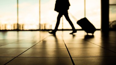 Havaalanındaki gezgin pencerenin önündeki kalkışa yürüyor, ılık renkler