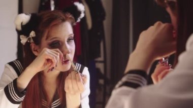 Anime makyajlı genç bir kadın su hattına beyaz göz kalemi sürüyor. Orta çekim