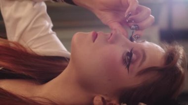 Anime makyajlı, takma kirpik takan genç bir kadın. Dikey çekim