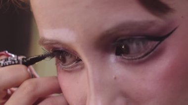 Kanatlı göz kalemi çizen genç bir kadın. Orta çekim