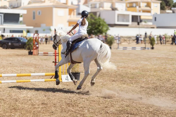 乗馬スポーツ 牧場で白い馬に乗って一様な女の子 障害物を飛び越える ミッドショット — ストック写真