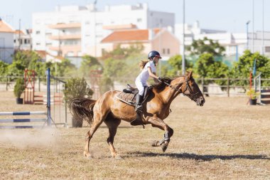 30 Nisan 2023 Sobreda, Portekiz: Festival Hipico da Sobreda - çiftlikte açık kahverengi ata binen küçük bir kız. Orta çekim