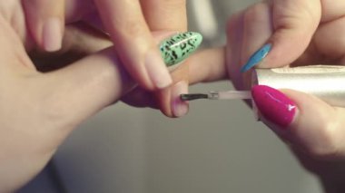 Manikür - manikürcü müşterilere çıplak jel cilası sürer. Orta çekim